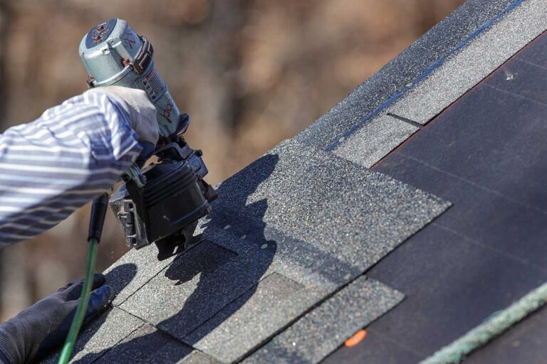 Homeowner examines loose shingles and roof debris from the ground after a storm.